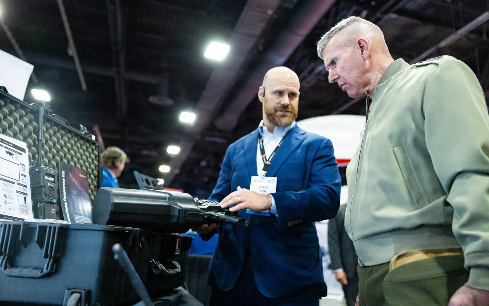 Vendor demonstrating a handheld counter-drone response kit to a uniformed attendee on a defense exhibition floor