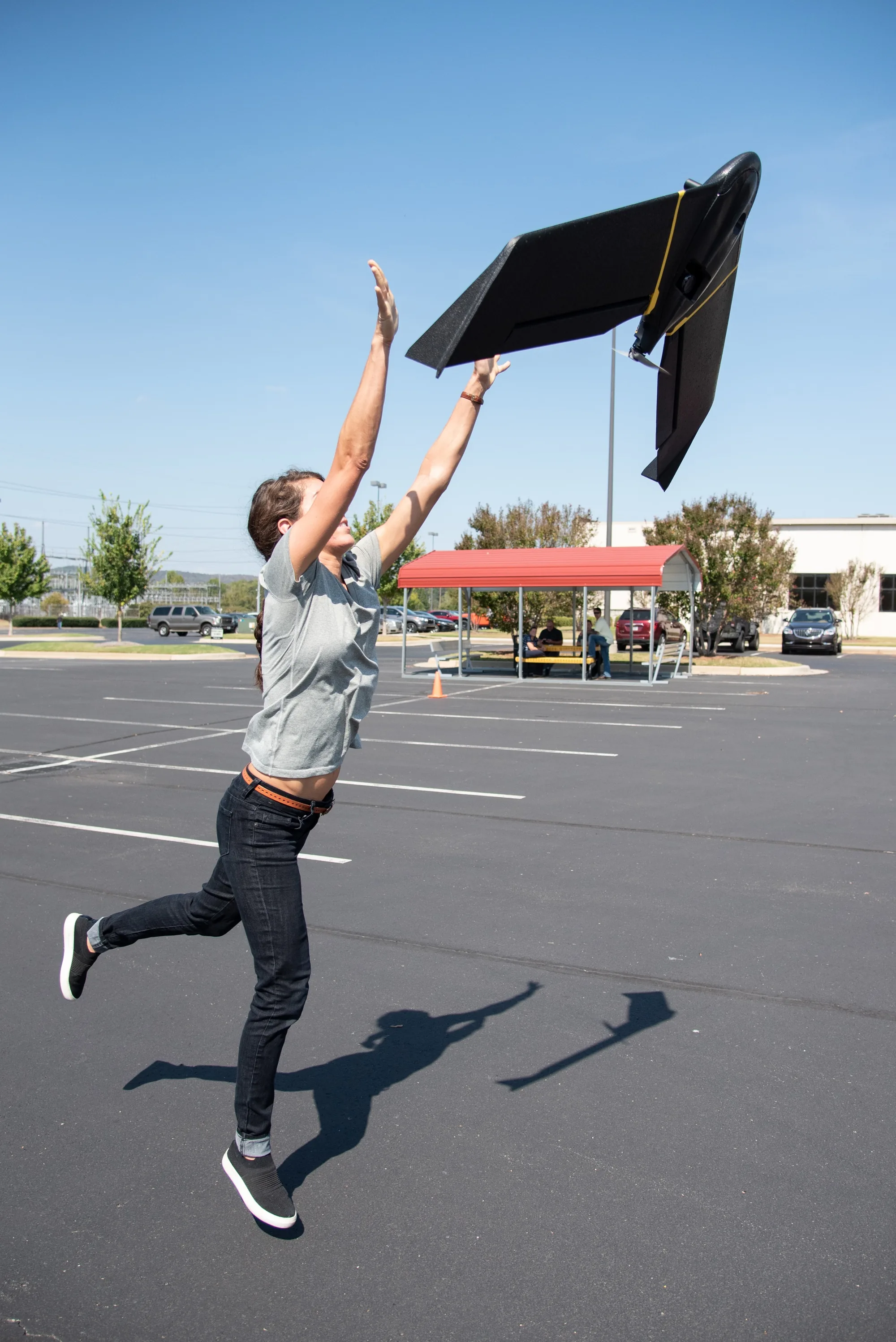 An operator releases a black flying-wing unmanned aircraft above her head during a hand launch outside the Huntsville Center.