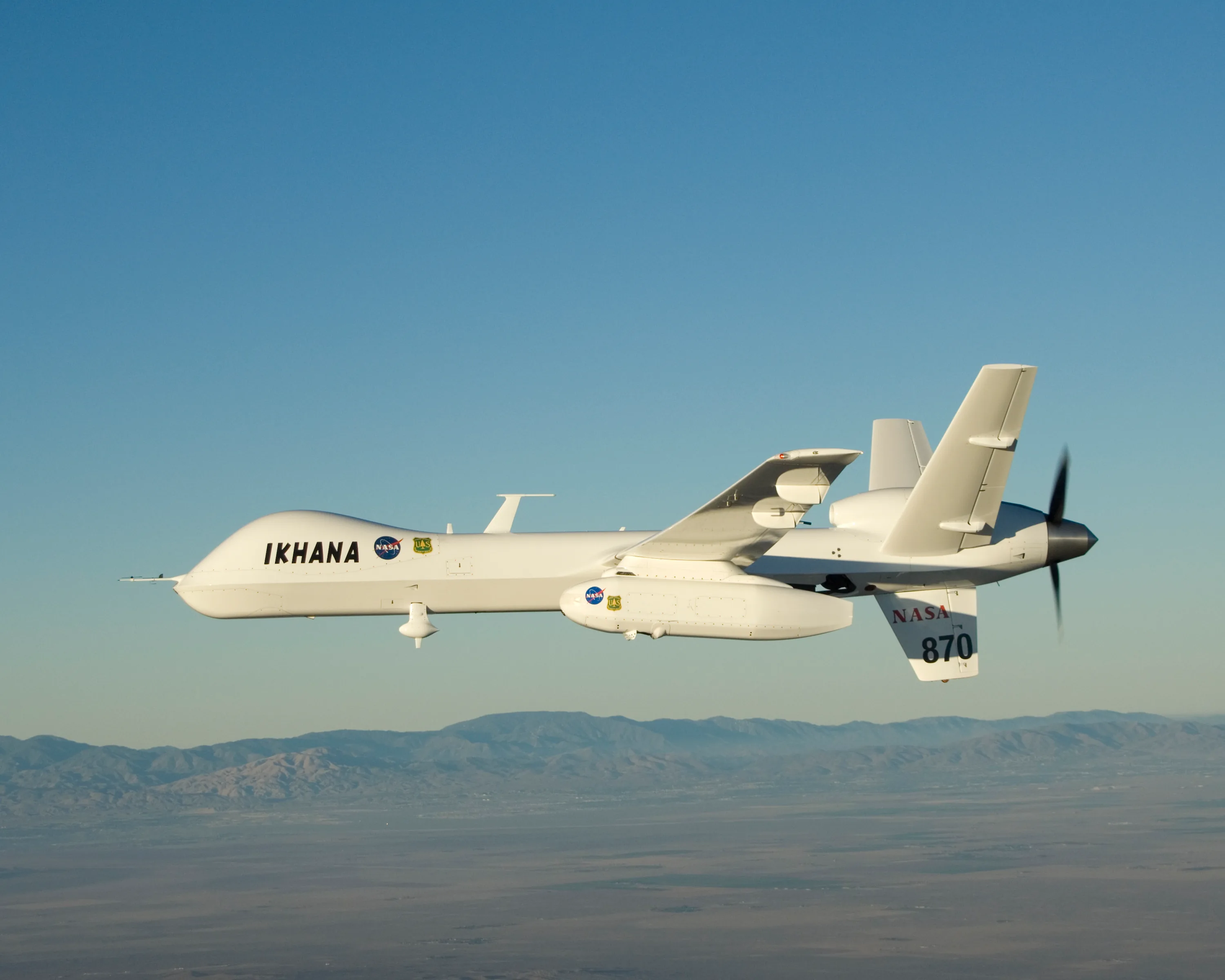 NASA Ikhana unmanned aircraft in flight with a long sensor pod mounted beneath its left wing.