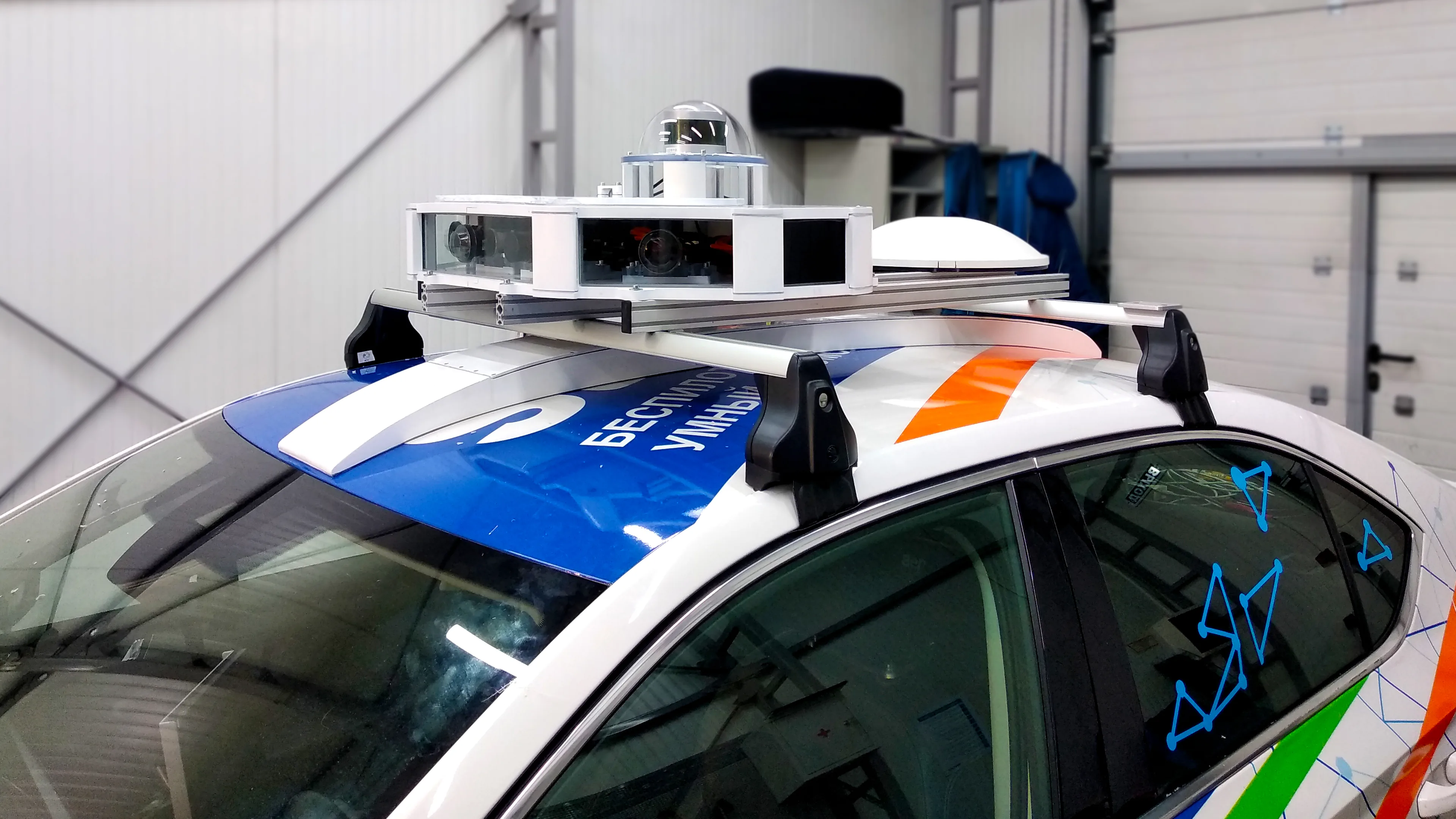 Roof-mounted camera housings, a laser scanner, and navigation equipment on a vehicle inside a workshop