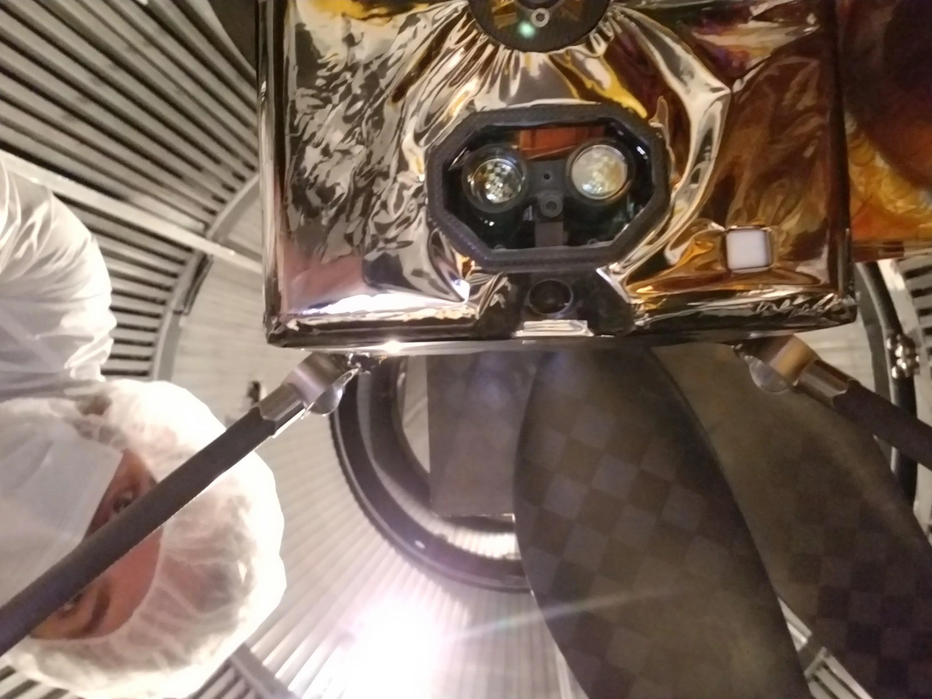 Underside of Ingenuity showing the small navigation camera between and below two larger laser-altimeter lenses